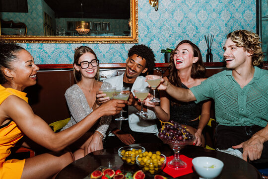 Diverse friends enjoying cocktails and toasting during a social party
