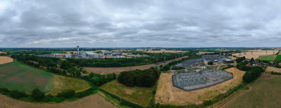 Aerial view of Staythorpe Power Station electrical substation surrounded by green fields and agricultural land under a cloudy sky in Staythorpe, England, United Kingdom.