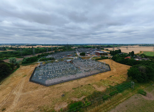 Aerial view of Staythorpe Power Station electrical substation surrounded by agricultural fields and trees under a cloudy sky in Staythorpe, England, United Kingdom.
