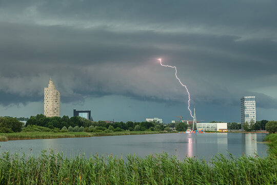 View of a lightning strike hitting near modern buildings and a lake in Latvia.