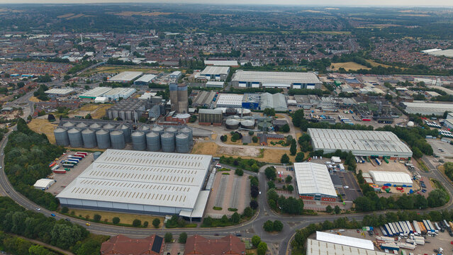 Aerial view of the industrial brewery complex featuring large storage silos, expansive warehouses, and parking facilities in the town of Burton upon Trent, England, United Kingdom.