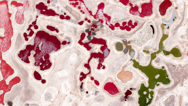 Aerial view of the vibrant mineral-rich salt pans of Magado Crater, featuring striking red and green pools contrasted against white salt crusts in Magado, Meru County, Kenya.