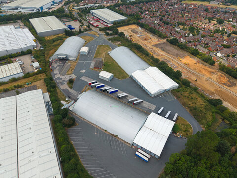 Aerial view of industrial warehouses and distribution centres with parked HGVs and logistics vehicles in Hilliard's Cross, England, United Kingdom.