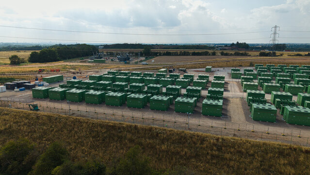 Aerial view of National Grid Hams Hall Battery Energy Storage Systems with rows of green lithium ion battery containers in a rural field in Birmingham, England, United Kingdom.