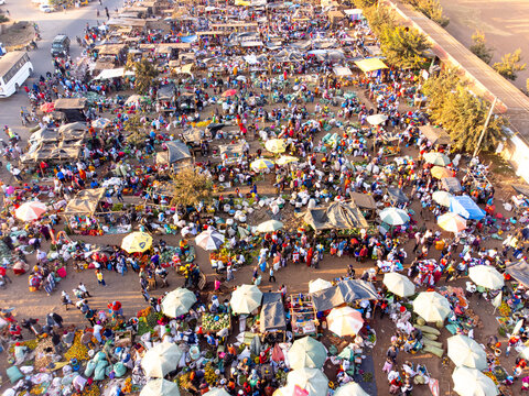 Aerial view of the bustling open-air market in Kimana, filled with numerous stalls, colorful umbrellas, and crowds of people trading goods in Kimana, Kajiado County, Kenya.