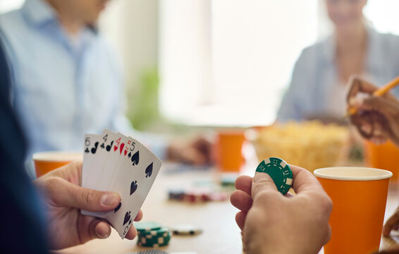 Friends poker cards chips game party table. Casual scene with closeup hands and players holding cards and stacking chips near drinks and gambling. Concept casual leisure and strategy.