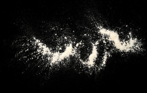 White flour or powder scattered in a flowing shape on a black background, creating a dramatic contrast with a messy textured look and strong copy space.