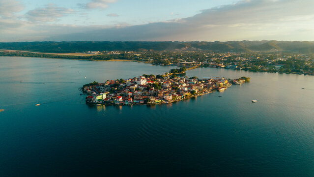 Aerial view of the historic island town of Flores with its colorful buildings and red rooftops surrounded by the calm waters of Lake Peten Itza in Flores, Peten Department, Guatemala.
