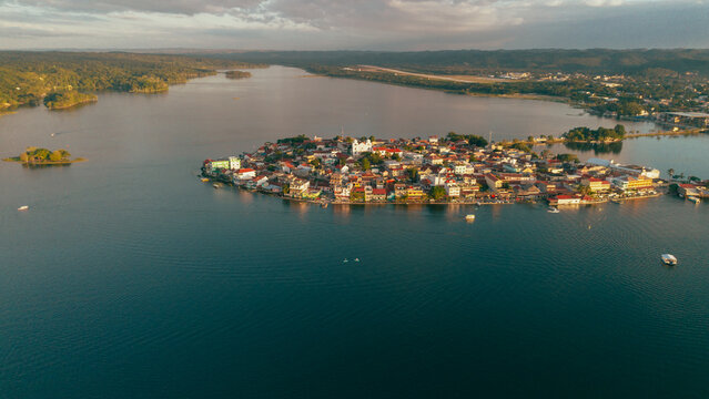 Aerial view of the island town of Flores with colorful buildings and red-tiled roofs, surrounded by the calm waters of Lake Peten Itza in Flores, Peten Department, Guatemala.