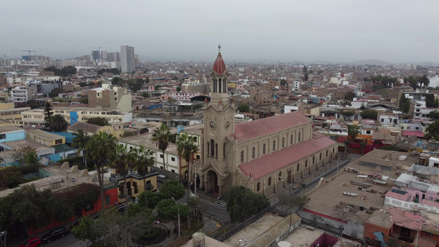 Aerial view of Parroquia San Francisco de Asis in Barranco, featuring its distinctive red roof and tower, surrounded by urban buildings and palm trees in Barranco, Provincia de Lima, Peru.