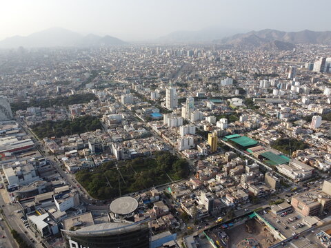 Aerial view of Javier Prado Este cutting through the dense urban landscape of San Isidro with high-rise buildings, residential blocks, and green spaces in San Isidro, Provincia de Lima, Peru.