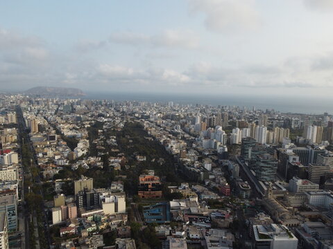 Aerial view of the historic Bosque El Olivar park surrounded by modern high-rise buildings and urban skyline in San Isidro, Provincia de Lima, Peru.