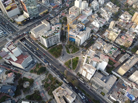 Aerial view of the urban landscape of San Isidro featuring modern high-rise buildings, a central park, busy traffic on roads, and construction activity in San Isidro, Lima Province, Peru.