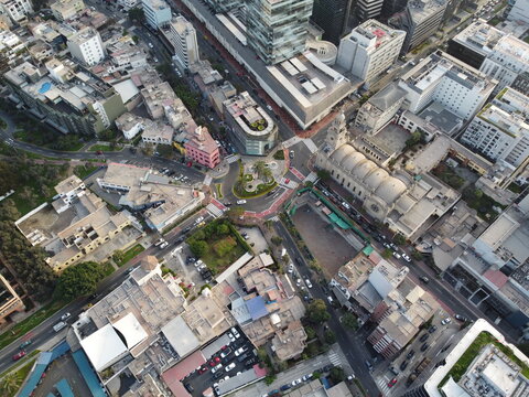 Aerial view of the urban landscape of San Isidro featuring a roundabout, modern buildings, and a historic church amidst city streets in San Isidro, Lima Province, Peru.