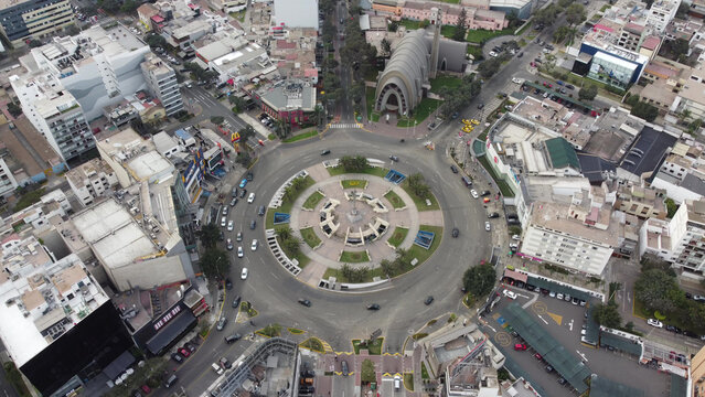 Aerial view of the Ovalo Gutierrez roundabout with its central monument, surrounded by urban buildings, traffic, and the Parroquia Santa Maria Reina in Miraflores, Provincia de Lima, Peru.