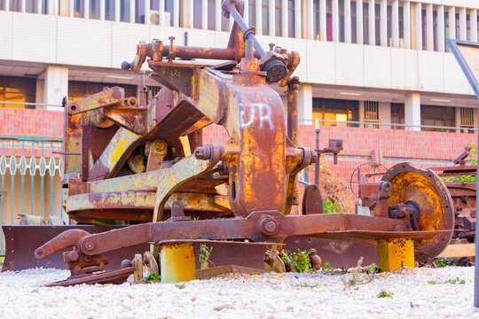 Lusaka, Zambia - 01 July 2026: View of a vintage, rusted road grader displayed outdoors in front of a modern building, showcasing industrial history in the city.