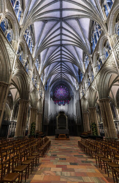 Trondheim, Norway - 30 December 2024: View of the interior of Nidaros Cathedral, featuring intricate vaulted ceilings, a large rose window, and rows of wooden chairs on a stone floor.