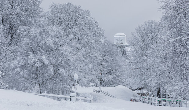 View of a snow-covered park with frost-laden trees and a distant building in Trondheim, Trondelag, Norway.