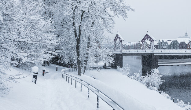 Trondheim, Norway - 30 December 2024: View of Gamle bybro surrounded by snow-covered trees and a winter landscape along the Nidelva river in Trondheim.