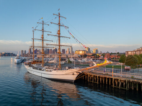 Aerial view of the tall ship BAE Guayas of Ecuador docked in Charlestown with the Boston skyline beyond under a clear sky in Boston, Massachusetts, USA.