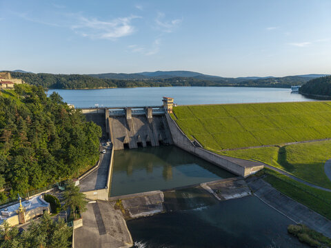 Aerial view of the Dobczyce Dam on Lake Dobczyce, featuring a concrete structure, grassy embankment, surrounding forests, and calm water Myslenice County, Lesser Poland Voivode, Poland.