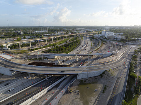Aerial view of Golden Glades Interchange under construction with multi-level concrete overpasses, highway traffic, and surrounding urban landscape in Miami, Florida, United States.