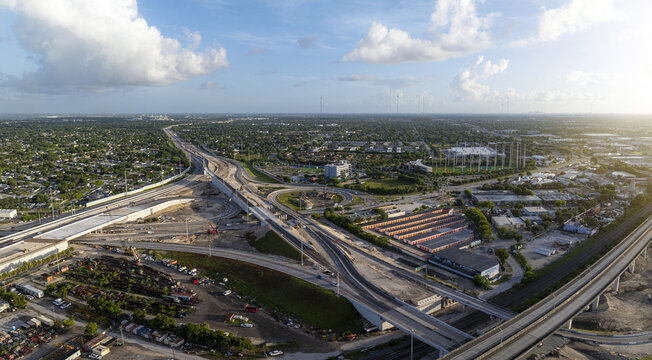 Aerial view of the Golden Glades Interchange in Miami, featuring complex highway ramps, construction, urban landscape, and greenery under a bright sky in Miami, Florida, United States.