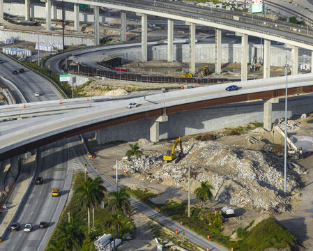 Aerial view of the Golden Glades Interchange featuring multi-level highway overpasses, ongoing construction work with heavy machinery, and palm trees in Miami, Florida, United States.