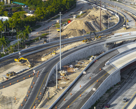 Aerial view of the Golden Glades Interchange construction site featuring heavy machinery, concrete barriers, and orange traffic cones in Miami, Florida, United States.