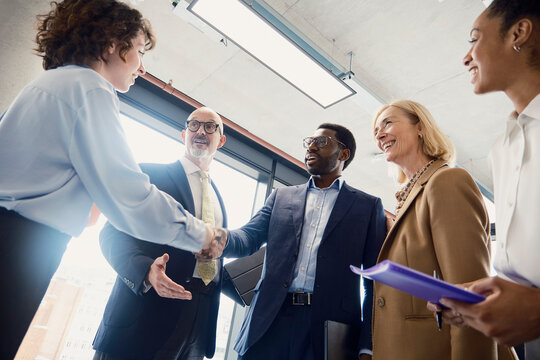A businessman shakes hands with a new client in a busy London office