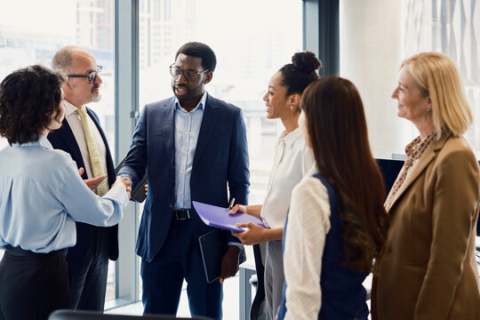 A businessman shakes hands with a colleague in a busy London office