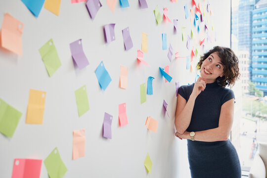 Smiling businesswoman brainstorms strategy on an office wall