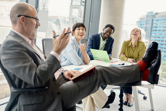 Businessman makes his team laugh during an office meeting