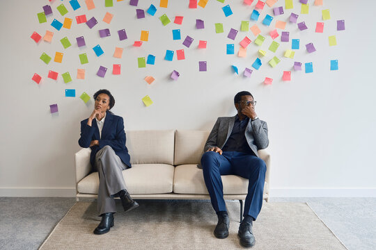 Man and woman sit on an office couch during a work disagreement