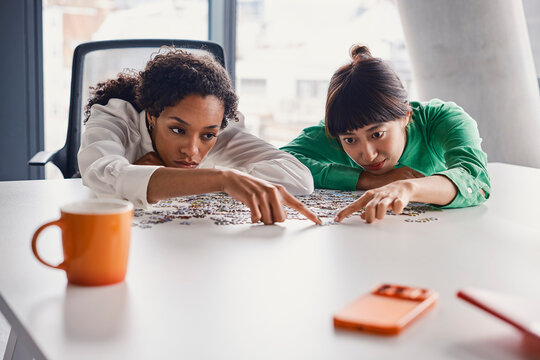 Women solve a jigsaw puzzle during team bonding in a London office