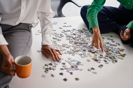 Business colleagues solve a jigsaw puzzle in a London boardroom