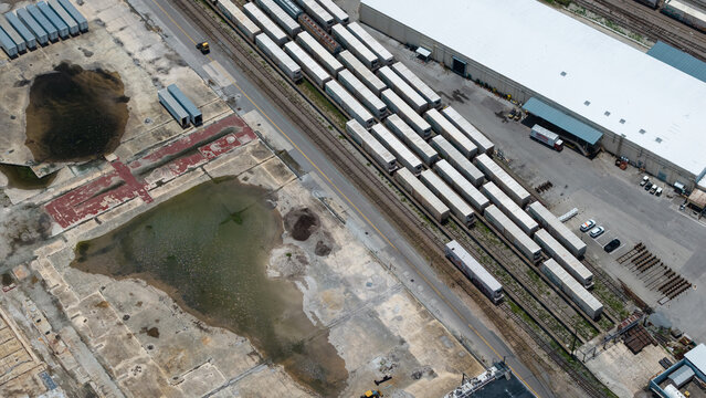 Aerial view of an industrial rail yard featuring rows of white shipping containers, railway tracks, and a large warehouse building in Bradenton, Florida, United States.