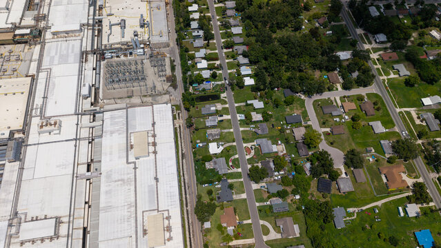 Aerial view of the Tropicana production facility adjacent to a residential neighborhood with green lawns and suburban streets in Bradenton, Florida, United States.