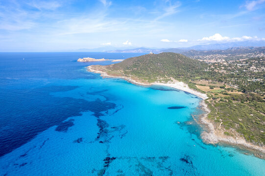 Aerial view of Plage de Ghjunchitu with turquoise waters, sandy coastline, and Mediterranean landscape in Corbara, Corse, France.