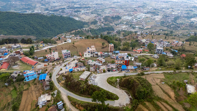Aerial view of Nagarkot with winding roads, scattered buildings, terraced fields, and lush green hills in Kathmandu, Bagmati Province, Nepal.