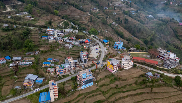 Aerial view of Nagarkot village nestled in the hills with terraced fields, scattered houses, and a winding road in Kathmandu, Bagmati Province, Nepal.
