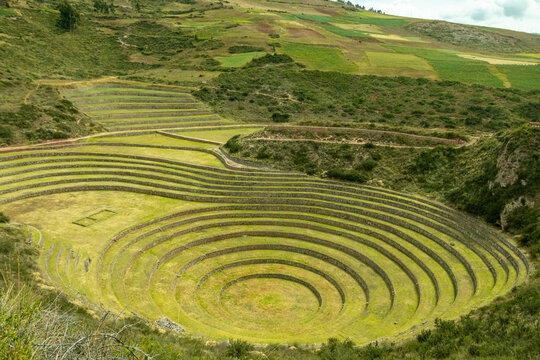 View of the circular agricultural terraces of Moray with stone retaining walls and lush green grass in the Andean landscape of Cusco, Cusco, Peru.