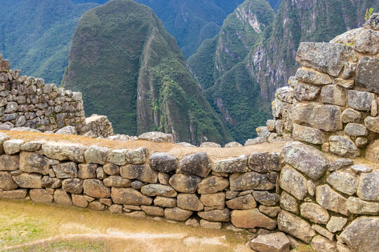 View of the ancient stone walls of Machu Picchu with lush green mountains in the background in Machu Picchu, Cusco, Peru.