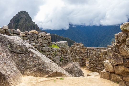 View of the ancient stone ruins of Machu Picchu with the towering Huayna Picchu mountain in the background under a cloudy sky in Cusco, Cusco, Peru.