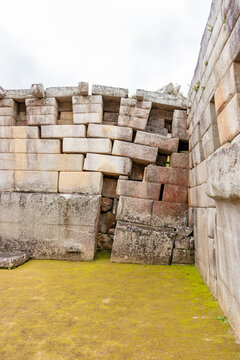 View of historic Inca stone masonry walls with precise interlocking blocks and mossy ground in Cusco, Cusco, Peru.