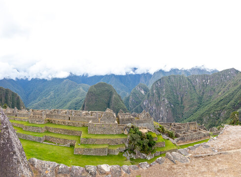 View of the historic Inca citadel of Machu Picchu with its stone terraces and ancient ruins set against the Andes mountains under a cloudy sky Cusco, Cusco, Peru.