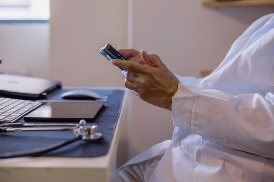 Doctor using smartphone for online communication, messaging and telemedicine in a modern clinic, representing digital healthcare, mobile technology, medical support and remote consultation.