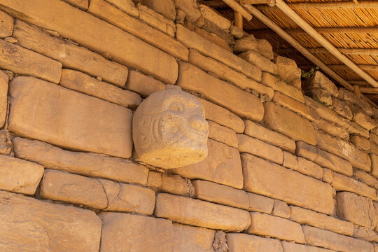 View of the ancient stone Cabeza Clava carving embedded in the historic masonry wall at the Chavin de Huantar archaeological site in Ancash, Peru.