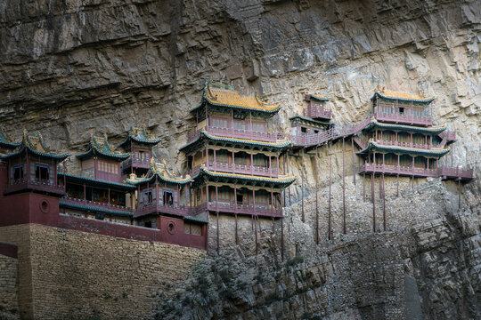 View of the historic Xuankong Temple, also known as the Hanging Temple, built into the side of a steep cliff with traditional wooden architecture and ornate roofs in Datong, China.