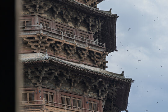 View of the intricate wooden architecture of the Pagoda of Fogong Temple featuring detailed dougong brackets and multiple stories against an overcast sky in Shuozhou, Shanxi, China.